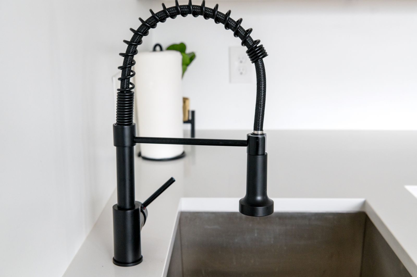 Modern pull-down faucet on a white quartz countertop — premium fixture installation by SolidStreams Plumbing, Austin